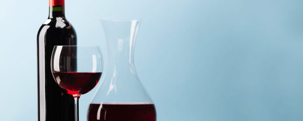 Imagen de una botella, un vaso llenos de vino tinto imprescindibles para aprovechar las propiedades saludables