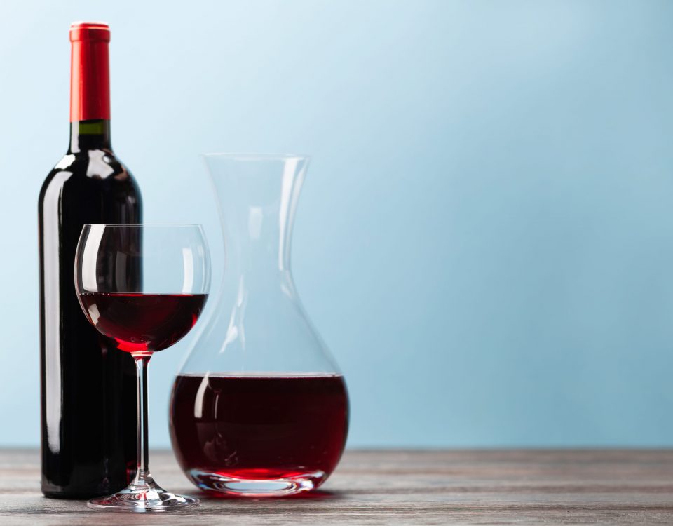 Imagen de una botella, un vaso llenos de vino tinto imprescindibles para aprovechar las propiedades saludables