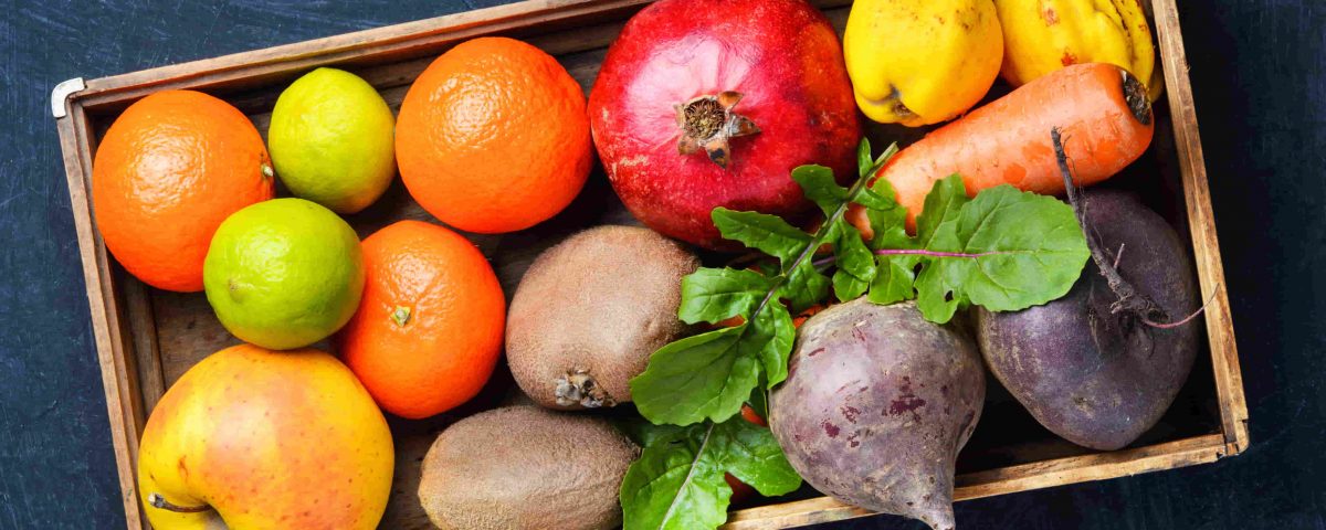 caja llena de frutas como granada, manzana, kiwis, etc.