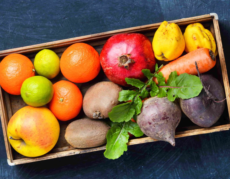 caja llena de frutas como granada, manzana, kiwis, etc.