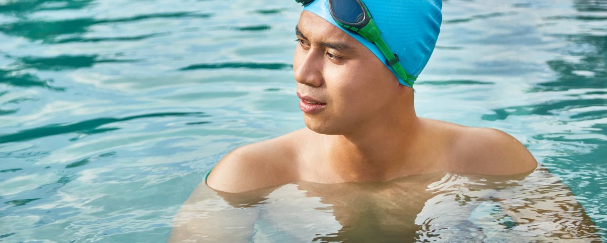 hombre en una piscina con gorro y gafas de bucear