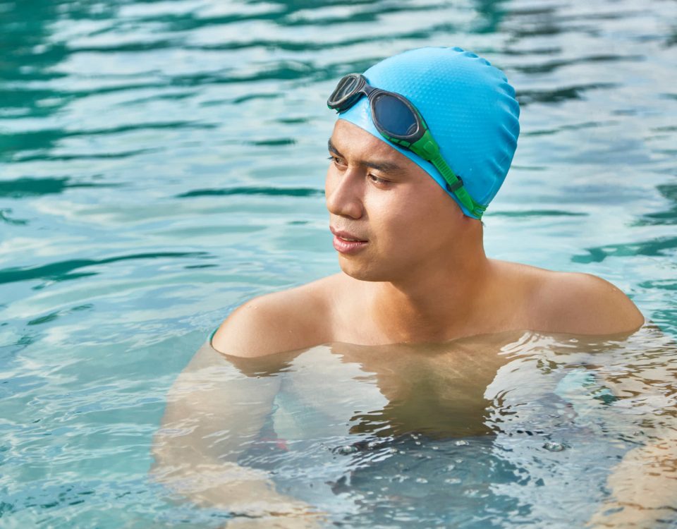 hombre en una piscina con gorro y gafas de bucear