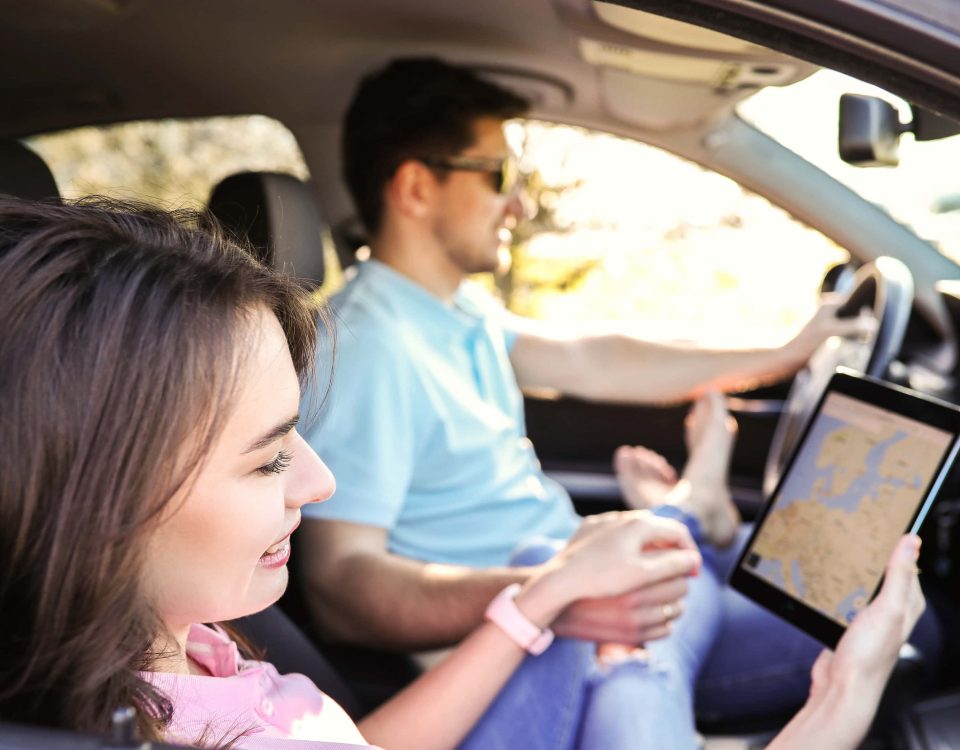 pareja viajando en coche. Él conduce mientras ella sujeta la tablet con un mapa