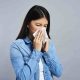 Mujer sonándose a causa de la alergia o intolerancia alimentaria