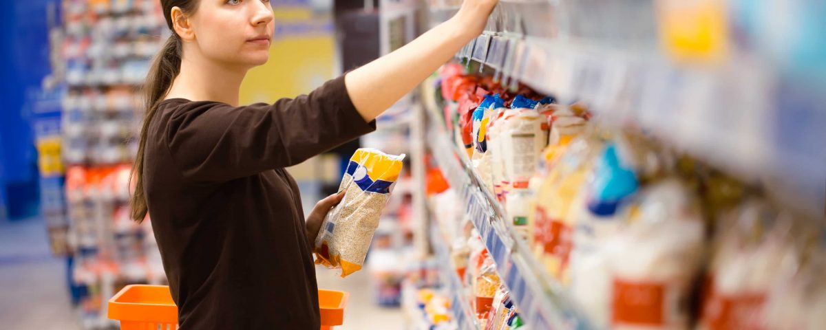 mujer realizando compra en el supermercado y revisando los etiquetados
