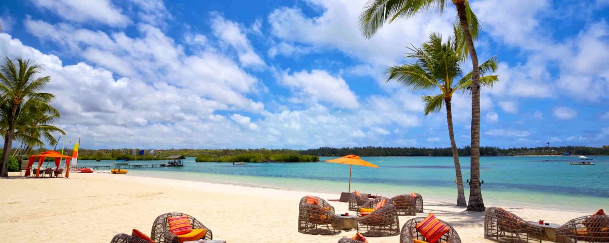 imagen de una playa paradisiaca y una terraza con mesas y sillas