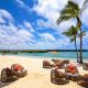 imagen de una playa paradisiaca y una terraza con mesas y sillas