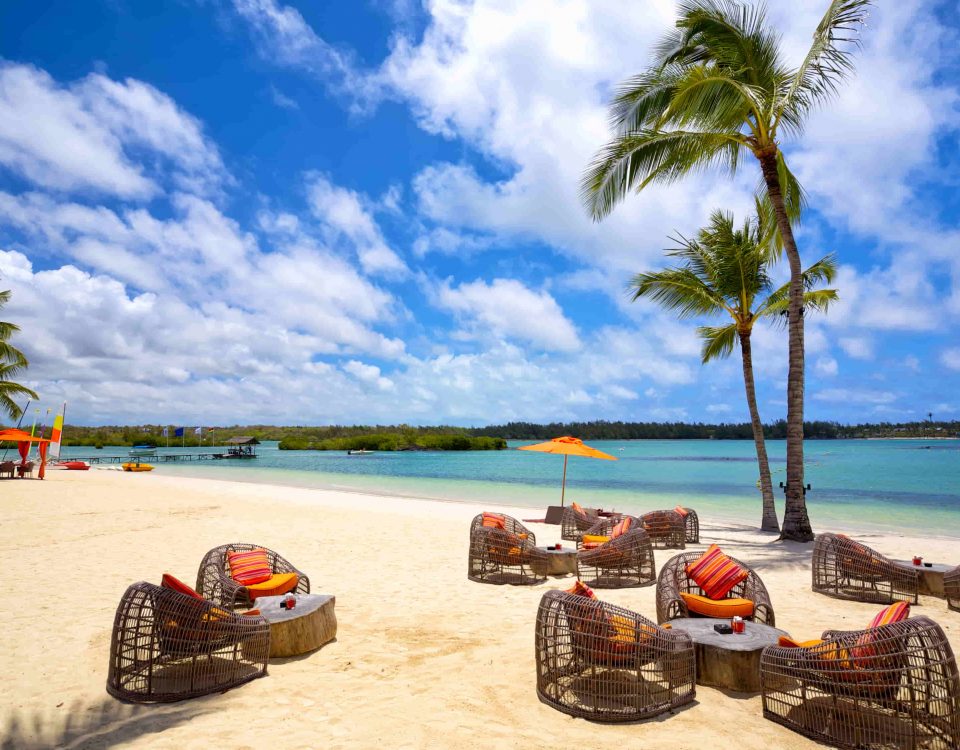 imagen de una playa paradisiaca y una terraza con mesas y sillas