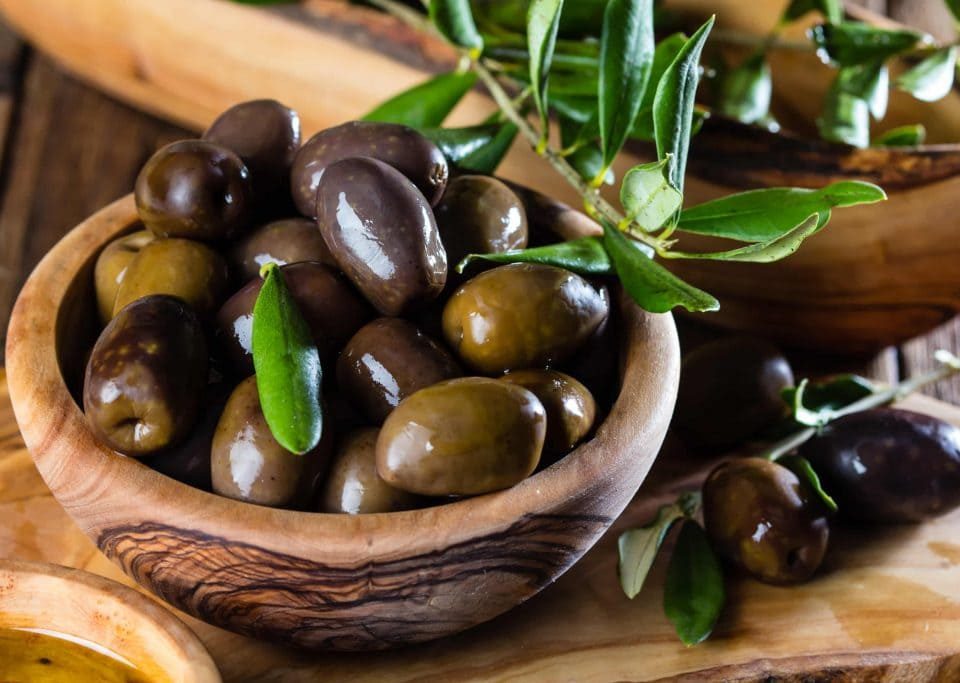 aceitunas en un tarro con ramas de olivo