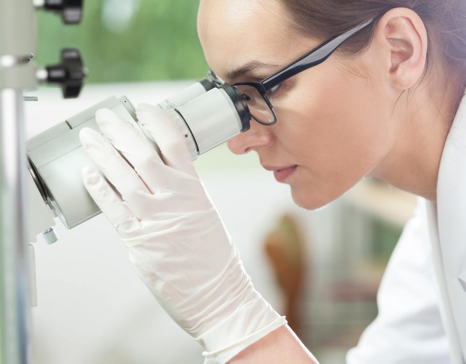 mujer mirando a través de un microscopio