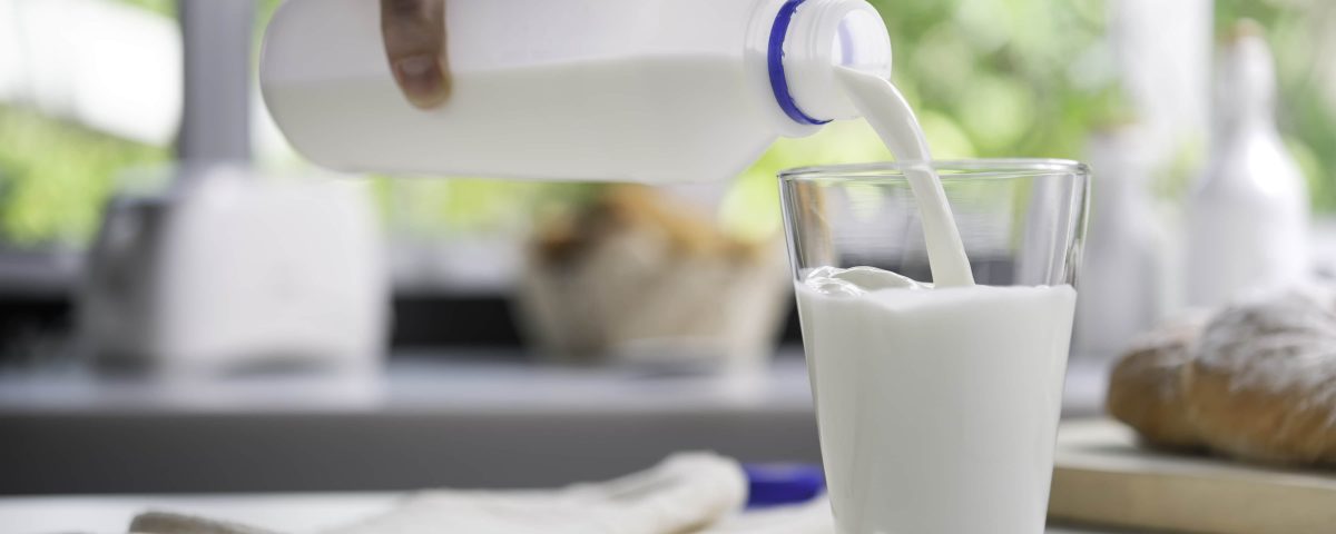 imagen de una mano echando leche cruda en un vaso