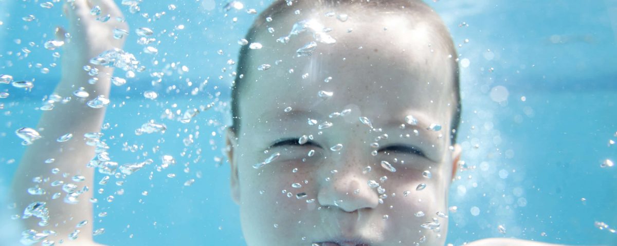 niño pequeño bajo el agua de una piscina