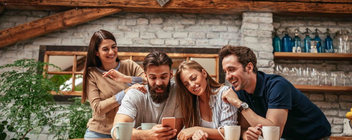 dos hombres y dos mujeres mirando un mismo móvil