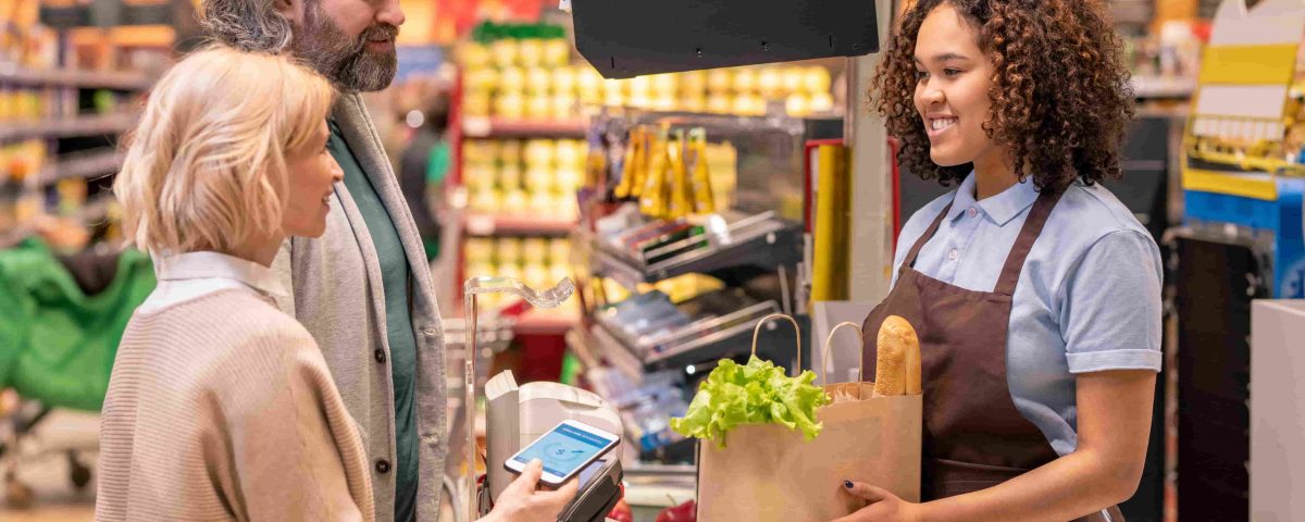 mujer entregando una bolsa de la compra a una pareja