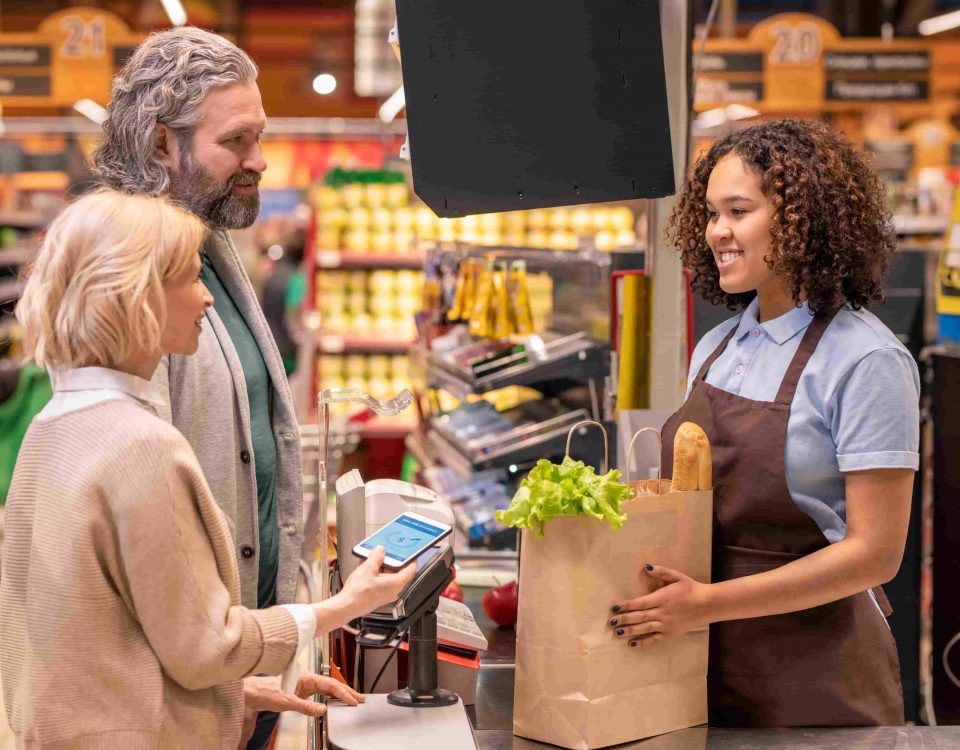 mujer entregando una bolsa de la compra a una pareja