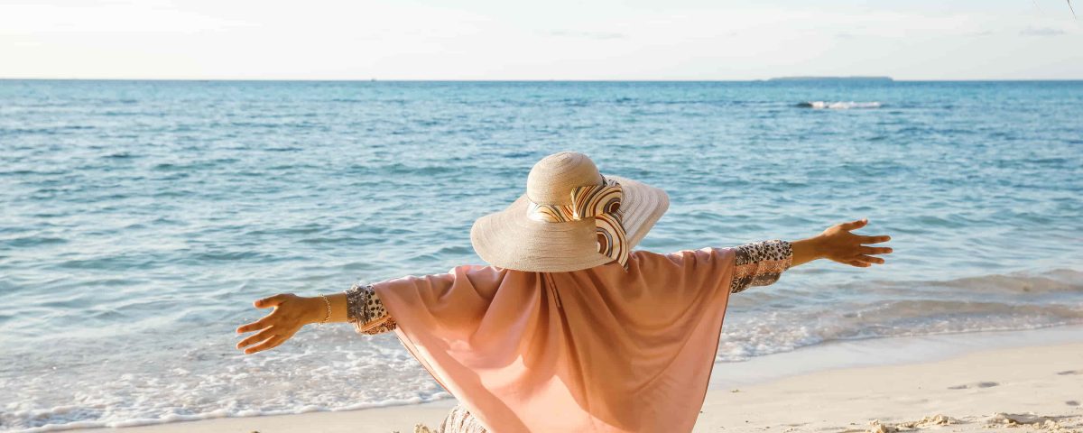 mujer con los brazos abiertos en la playa