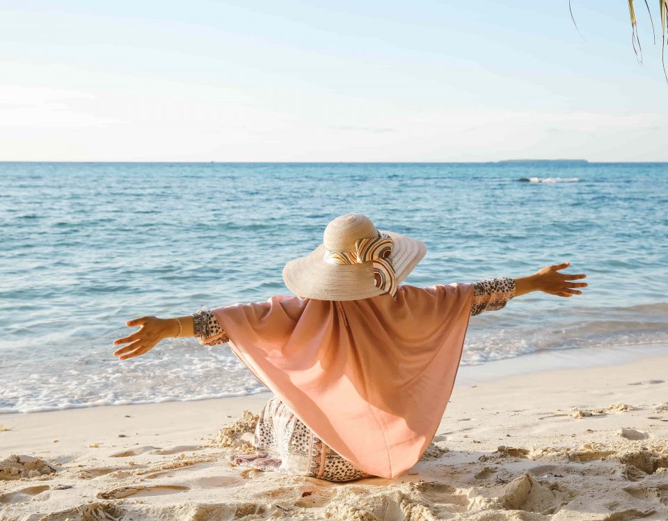 mujer con los brazos abiertos en la playa