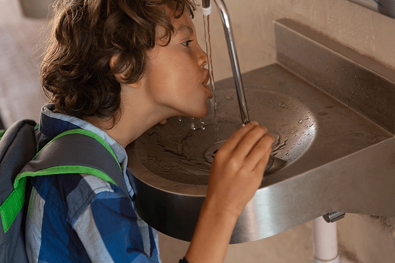fotografía de un niño bebiendo agua del grifo
