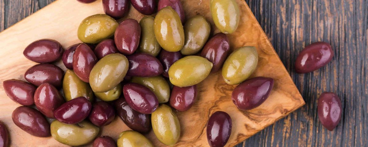 aceitunas verdes y moradas sobre una tabla de madera